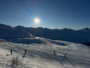 Les Menuires -skiers on a ski slope by sunny weather